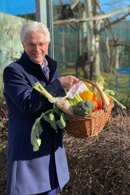 Der Vorstandsvorsitzende der Stadtsparkasse Augsburg, rolf Settelmeier hält einen Korb mit Gemüse für die Schmpansen in der Hand.