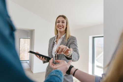 Female real estate showing a beautiful house to a young couple, explaining them every detail about house and making deal with them about house rent