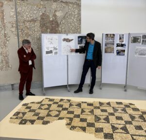 Der Leiter der Stadtarchäologie Dr. Sebastian Gairhos beschreibt den Fundort und die Bergung des restaurierten Mosaikbodens. Kulturreferent Jürgen K. Enninger lauscht gespannt